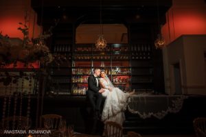 Cescaphe ballroom photo of teh bride and groom sitting on the bar