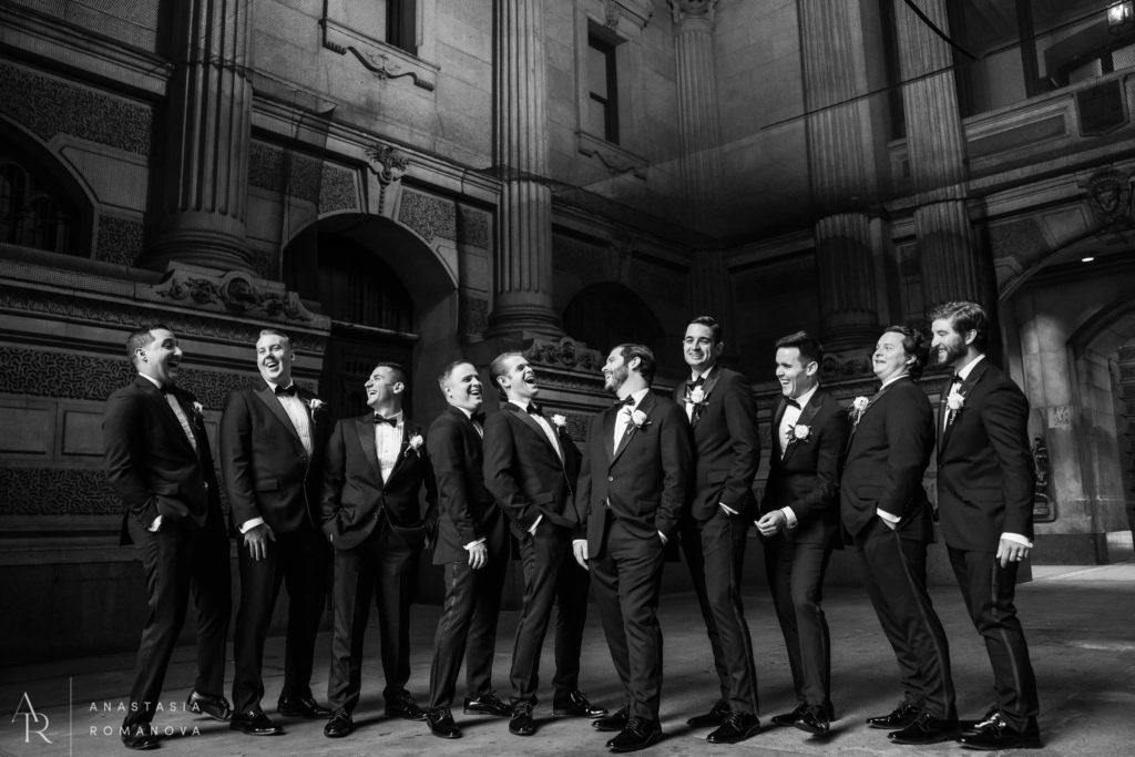 Groomsmen candidly laughing under the archway at the City Hall in Philadelphia