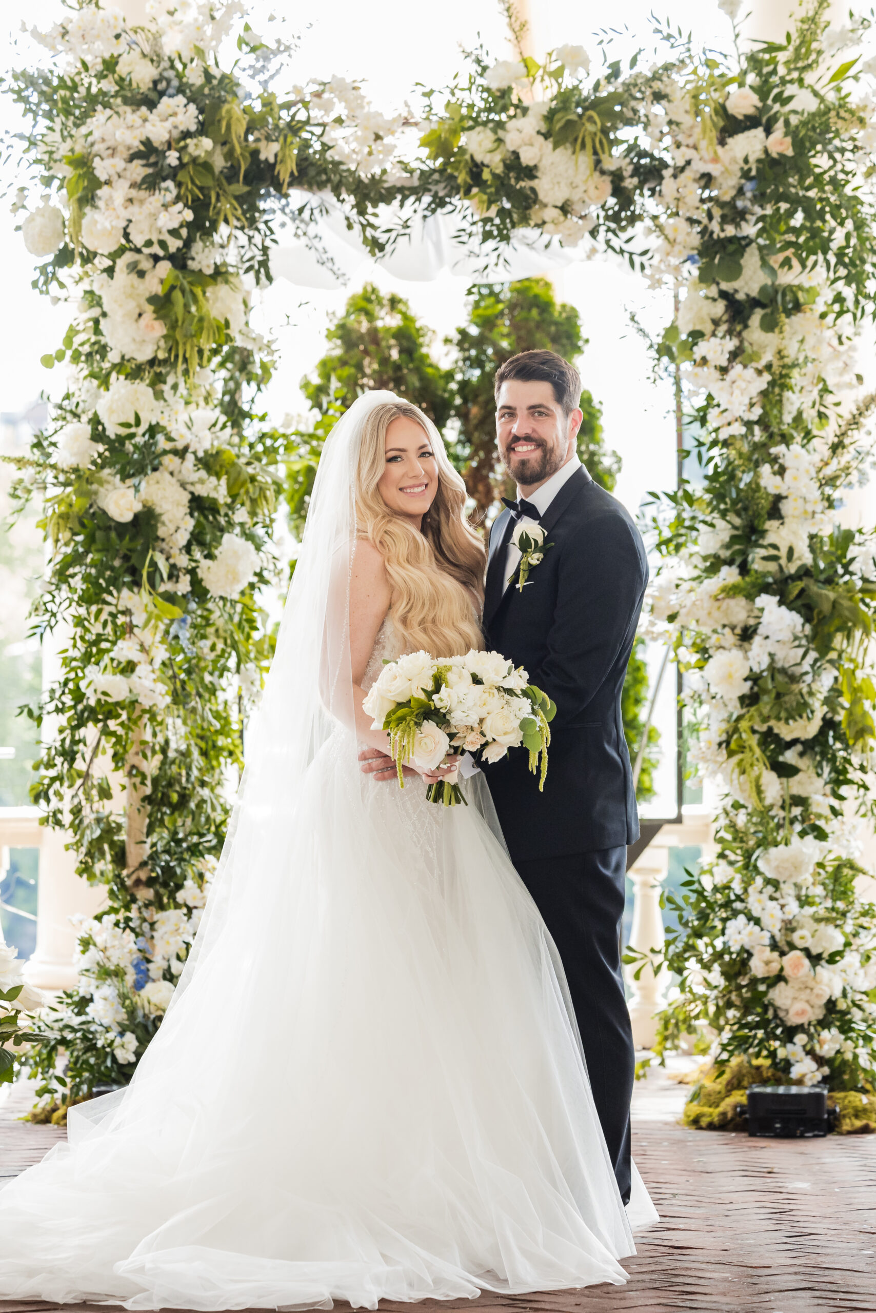 bride and groom in front of the luxury lush green ceremony arch at Water Works Philadelphia wedding